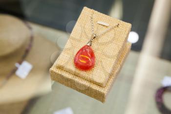 Chinese stone amulet made of red agate lays on a glass counter