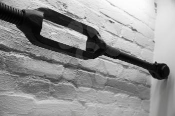 Old black turnbuckle, closeup photo over white brick wall background