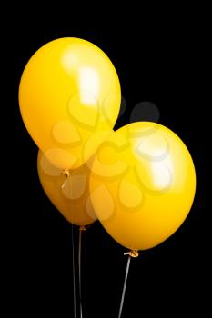 Three yellow balloons isolated on black background