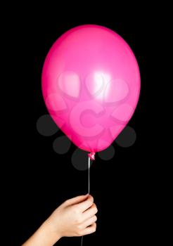 Child hand holding pink balloon isolated on black background
