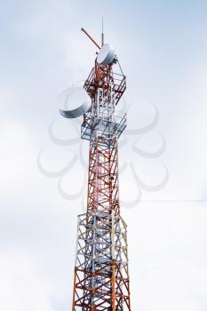 Telecommunication radio tower with transmitters and receivers over cloudy sky