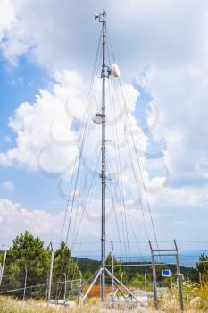 Telecommunication radio tower with devices above cloudy sky