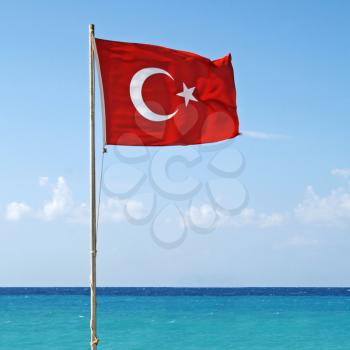 National flag of Turkey waving in the wind with Mediterranean sea and sky on the background