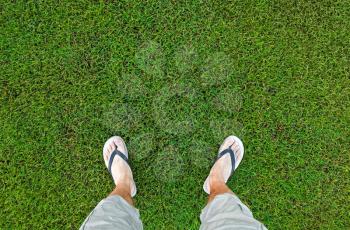 Feet of the man standing on fresh green grass