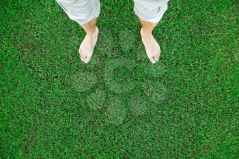 Bare feet of the man standing on fresh green grass