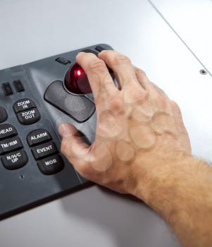 Man's hand on illuminated industrial keyboard with red trackball. Selective focus