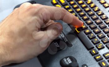 Finger pressing N key on illuminated industrial keyboard. Selective focus