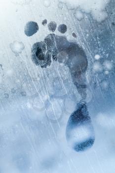 Male foot print on frozen windows glass