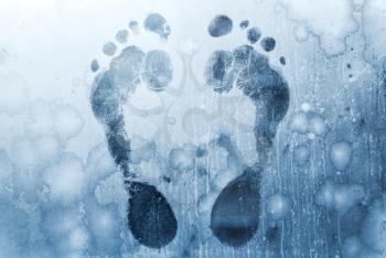 Male foot prints on frozen windows glass