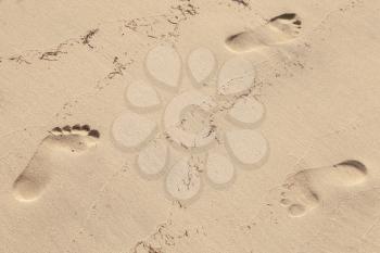 Man footprints in wet yellow sand on the beach