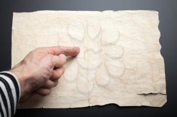 Sailor shows forefinger on old crumpled paper sheet