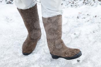 Male feet with Russian felt boots on winter road with snow and ice 