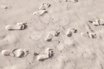 Footprints in white coastal sand on the ocean beach