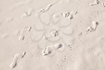 Many footprints in white coastal sand on the beach