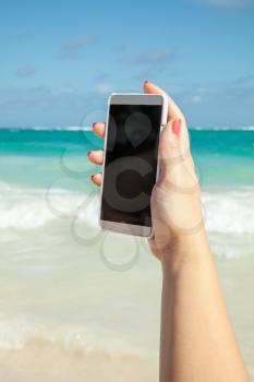 Woman using smart phone for taking photo on a beach in Dominican republic. Vintage style, filter effect