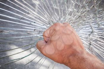 Strong male fist and broken window glass