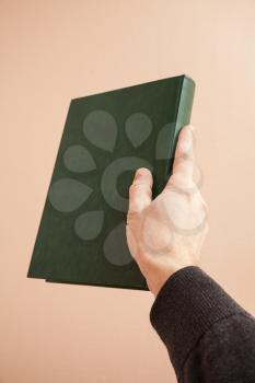 Book with empty dark green leather cover in male hand