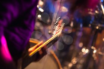 Colorful blurred rock music background, guitar player on a stage with colorful illumination