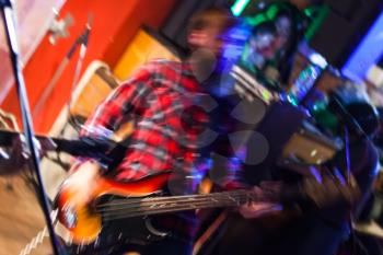 Colorful blurred rock music background, bass guitar player on a stage