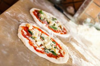Preparing Pizza Margherita, two portions are ready for baking. Selective focus