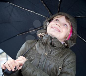 Portrait of a smiling little blond girl with umbrella in a casual jacket with the hood