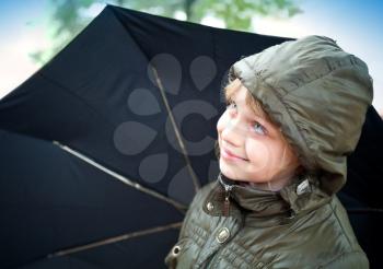 Portrait of a smiling little blond girl with umbrella in a casual jacket with the hood