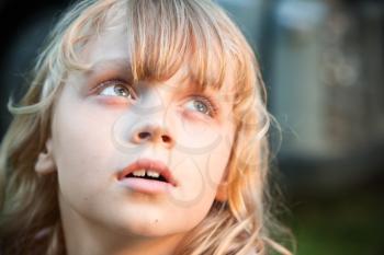 Closeup portrait of beautiful little blond girl looking up with amazement