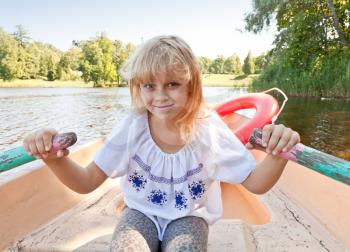 Little blond girl rowing on the boat