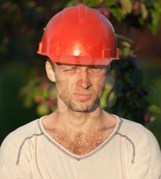 Closeup portrait of young construction worker with squinting eyes