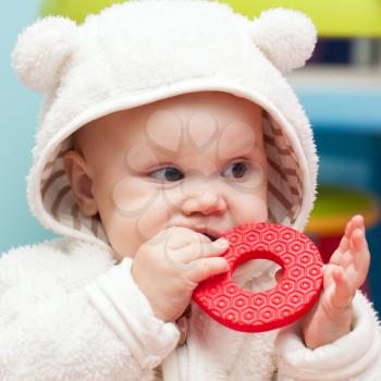 little baby baby chews on a soft plastic toy in white bear costume