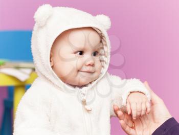 little baby in white bear costume smiles and hold mothers hand