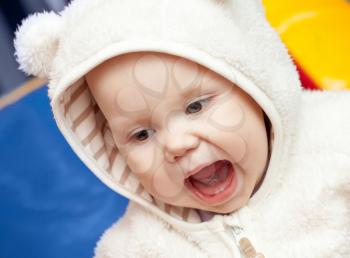 little baby laughs with open mouth in white bear costume