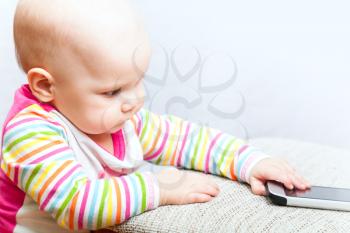 Little baby in casual colorful striped clothing with mobile phone