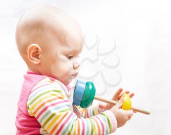 Little sad brown eyed baby plays with wooden toy, studio profile portrait