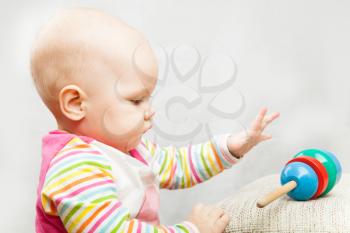 Little baby plays with wooden toy, closeup studio profile portrait
