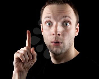 Surprised man with finger up idea gesture isolated on black background