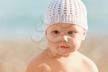 Outdoor summer portrait of Caucasian baby in white hat on the beach