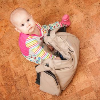 Little brown eyed Caucasian baby delves into the bag