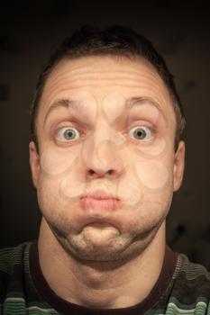 Young funny Caucasian man inflates cheeks. Closeup portrait