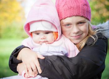 Two little sister girls in the park. Outdoor portrait