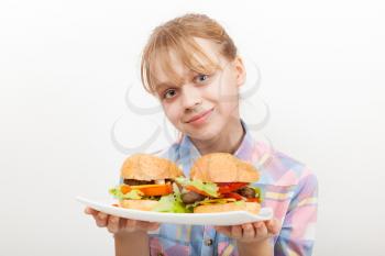 Little smiling blond girl with homemade hamburgers on white plate