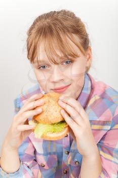 Little blond Caucasian girl eats homemade burger