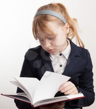 Close-up portrait of blond Caucasian schoolgirl reading textbook