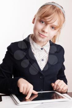 Little blond smiling girl with tablet device in school