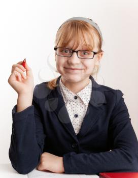 Little blond schoolgirl with glasses holds up the pen