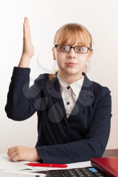 Little blond schoolgirl with glasses raises her hand