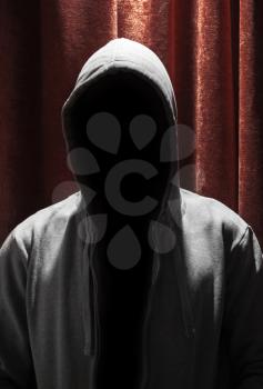 Portrait of Invisible man in the hood with red curtain background