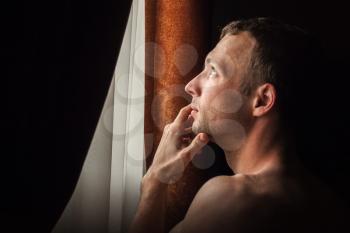 Young Caucasian man looking in the window, closeup profile portrait 