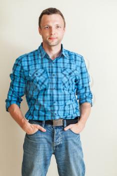 Studio portrait of young Caucasian man in blue shirt and jeans