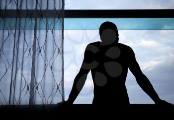 Man's silhouette in the window above blue cloudy sky